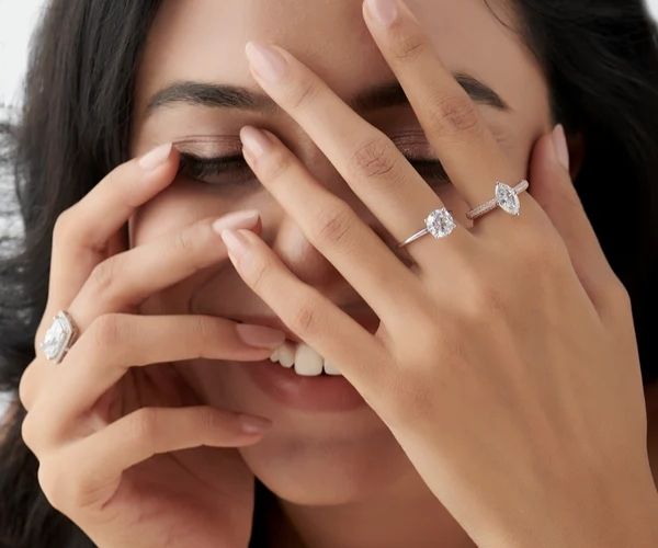 Close-up of a woman's hands with diamond rings on a neutral background