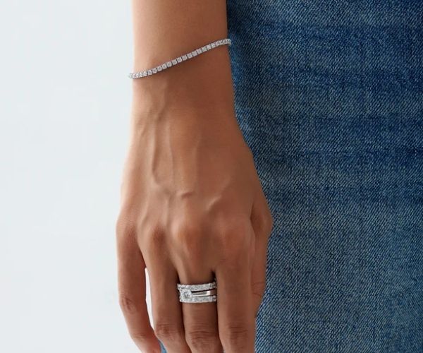 Hand wearing a ring and bracelet on a blue denim background