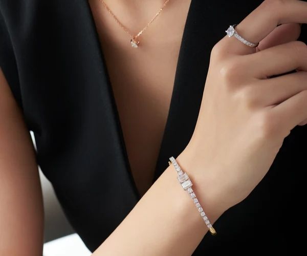 Close-up of a person wearing a bracelet, ring, and necklace on a black background