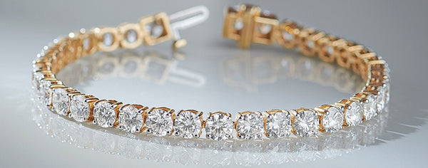 Gold bracelet with clear gemstones on a reflective surface