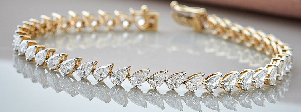 Gold bracelet with clear gemstones on a reflective surface
