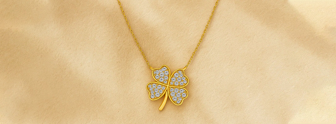 Gold necklace with a four-leaf clover pendant on a beige fabric background