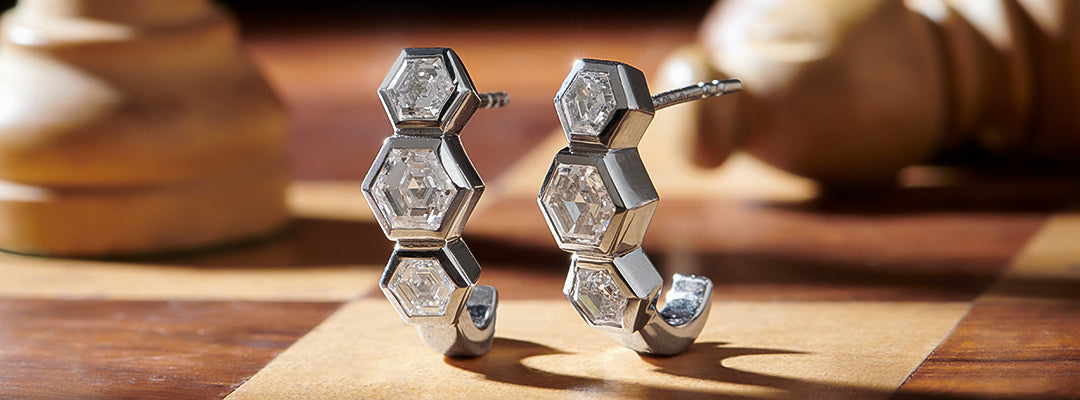 Hexagonal silver earrings on a wooden surface with a blurred background