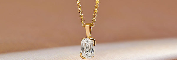 Gold necklace with a diamond pendant on a beige background