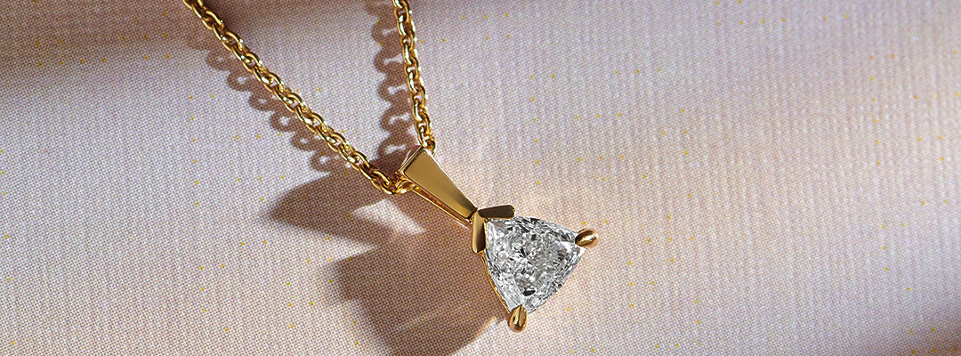 Gold necklace with a diamond pendant on a light fabric background