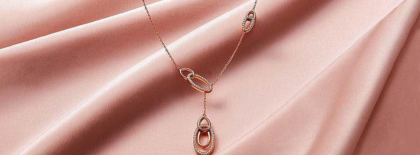 Rose gold necklace on a pink fabric background