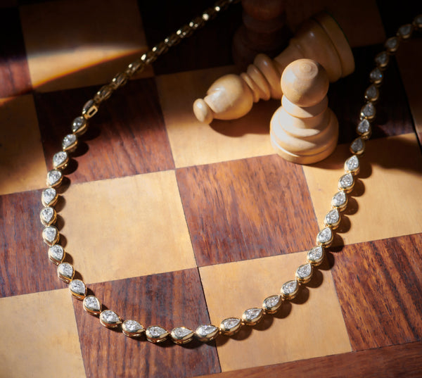 Diamond necklace on a wooden chessboard with chess pieces.