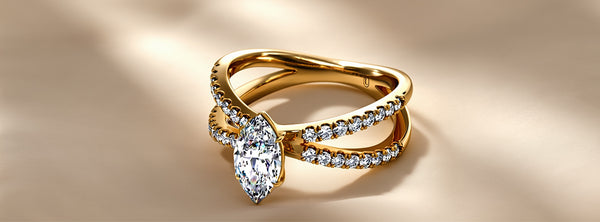 Gold ring with a pear-shaped diamond on a beige background