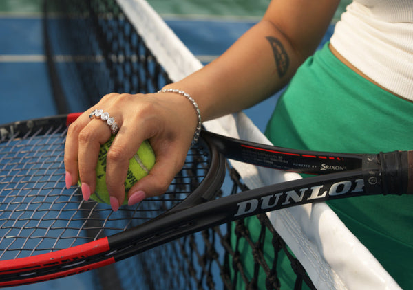 Person holding a Dunlop tennis racket and ball on a tennis court