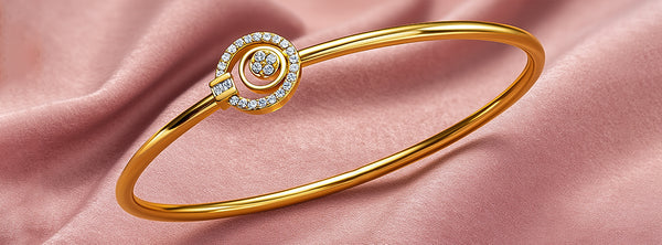 Gold bracelet with a decorative clasp on a pink fabric background