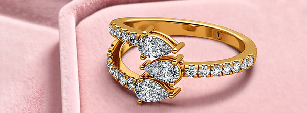 Gold butterfly-shaped ring with diamonds on a pink background