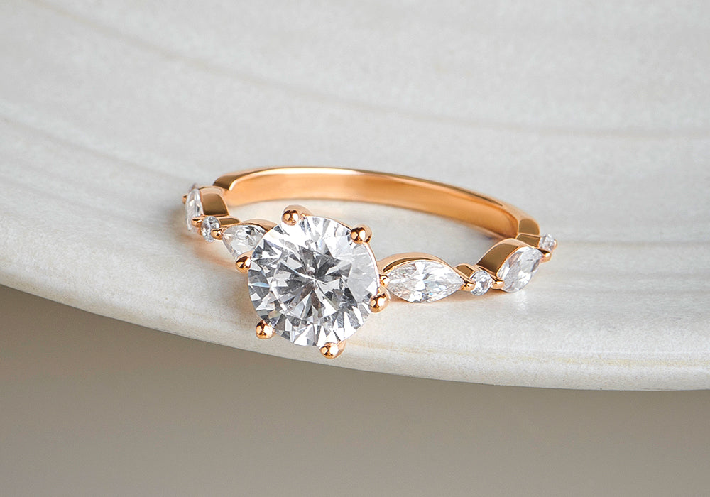 Rose gold ring with a large diamond and smaller diamonds on a light background
