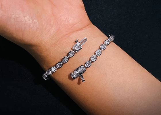 Silver bracelet with clear stones on a wrist against a dark background