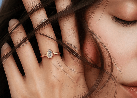 Close-up of a hand with a rose gold ring featuring a diamond, with hair partially covering the face.