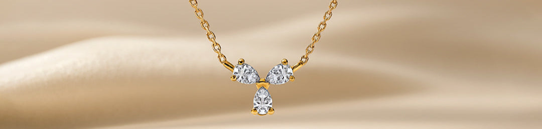 Gold necklace with three diamonds on a beige background