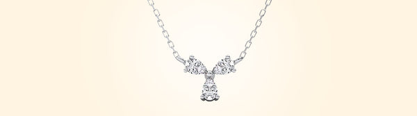 Silver necklace with a bow-shaped pendant on a beige background