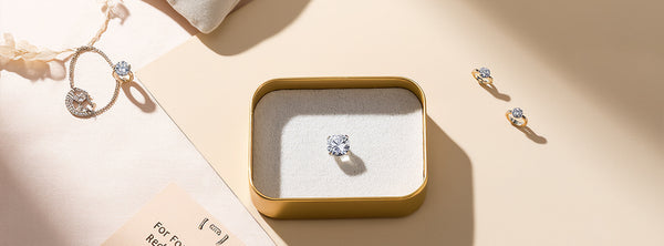 Diamond earrings in a gold box on a beige surface with a light background Diamond earrings in a gold box on a beige surface with a light background