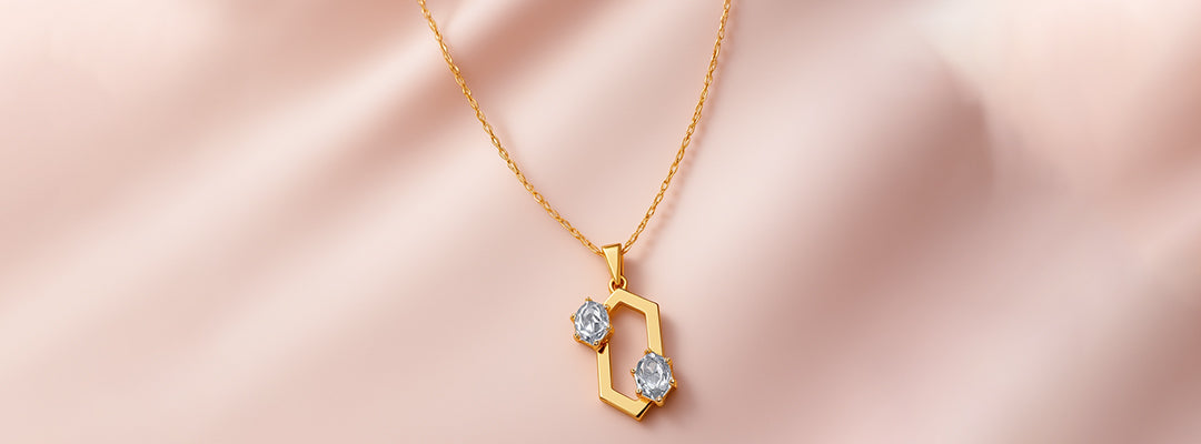 Gold necklace with a hexagonal pendant on a pink satin background