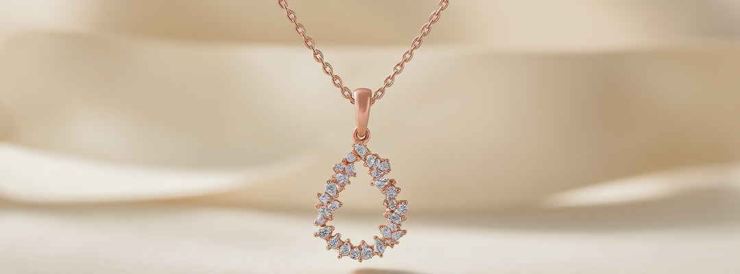 Rose gold teardrop-shaped necklace with diamonds on a beige background