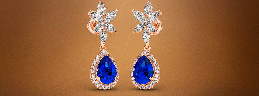 Pair of earrings with blue gemstones and floral designs on a brown background