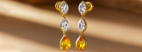 Gold earrings with teardrop-shaped gemstones on a beige background