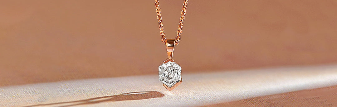 Rose gold necklace with a diamond pendant on a beige background