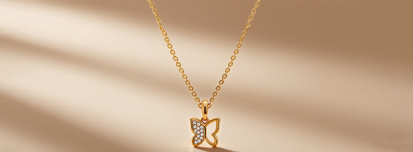 Gold necklace with a butterfly pendant on a beige background