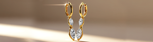 Gold hoop earrings with clear gemstones on a gradient background