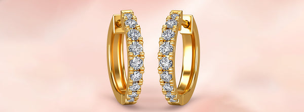 Gold hoop earrings with diamonds on a soft pink background