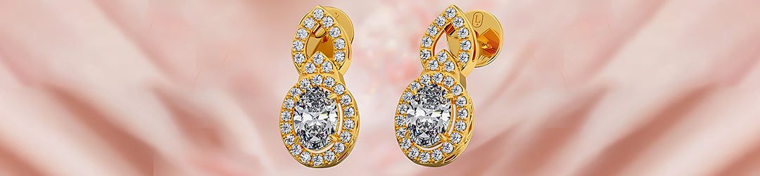 Gold earrings with clear gemstones on a soft pink background