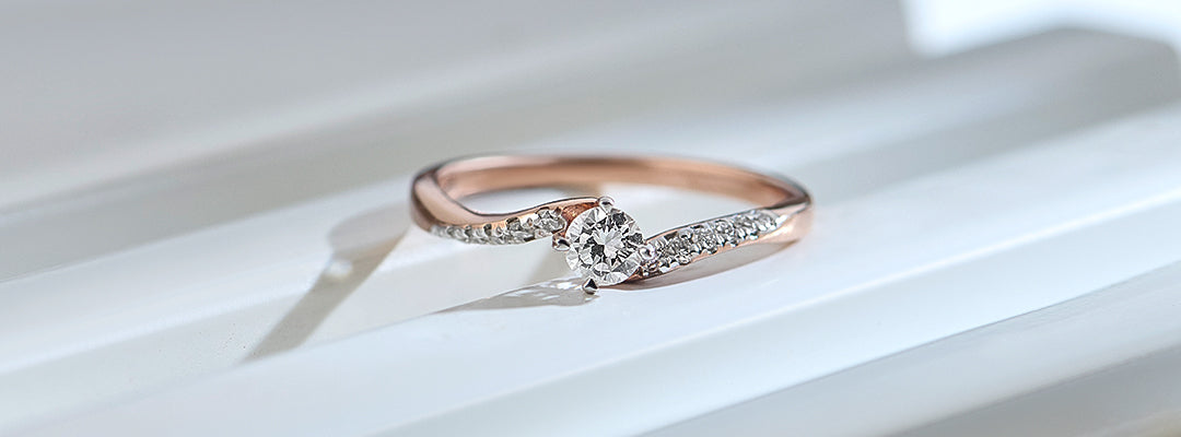 Rose gold ring with a diamond on a white surface