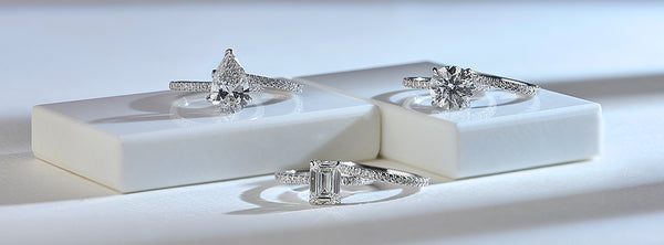 Three diamond rings on a white surface with a light blue background