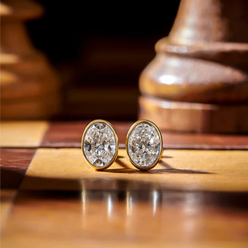 Gold earrings with clear gemstones on a wooden chessboard