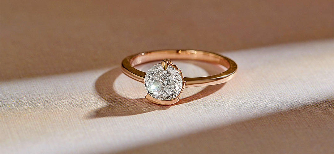 Rose gold ring with a diamond on a beige fabric background