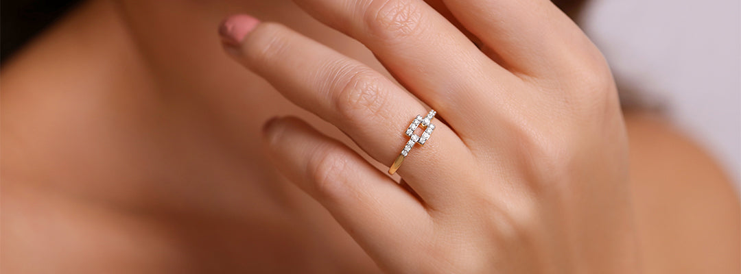 Close-up of a hand wearing a diamond ring with a blurred background